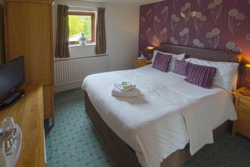 a hotel room with a large bed with a television at Yorkshire Bridge Inn in Bamford