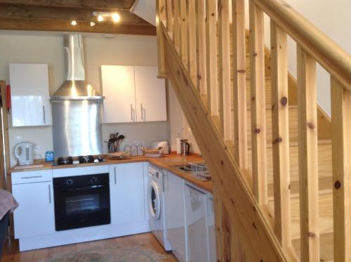 une cuisine avec des placards blancs et un escalier dans l'établissement La Perruche Holiday Gite, à Heussé