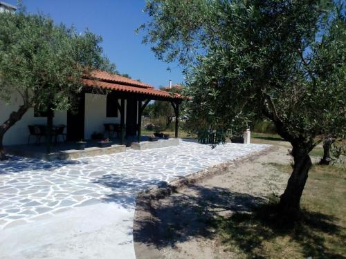 a stone patio with a gazebo and a tree at Pappou's Studios in Ormos Panagias