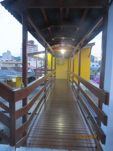 a wooden walkway leading to a yellow building at Pousada Recanto Dom Arthur in Itapema