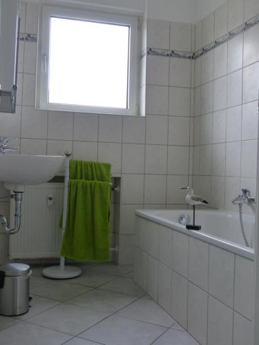 La salle de bains est pourvue d'un lavabo, d'une baignoire et d'une serviette verte. dans l'établissement Ferienwohnung Asenberg, à Bad Salzuflen