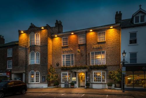 a large brick building with lights on it at The Golden Fleece Hotel, Thirsk, North Yorkshire in Thirsk