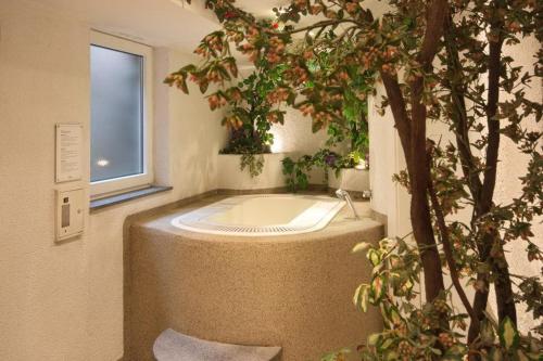 eine Badewanne im Bad mit einem Baum in der Unterkunft Hotel Vallechiara in Moena