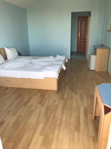 a bedroom with a bed and a wooden floor at Arkadia Guest House in Primorsko