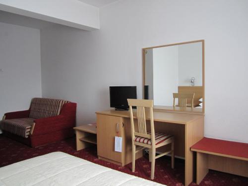 a hotel room with a desk with a mirror and a chair at Hotel Grand in Sarajevo