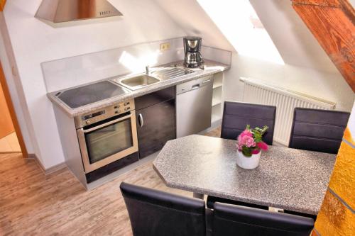 eine Küche mit einem Waschbecken und einem Tisch mit Stühlen in der Unterkunft Ferienwohnungen Louisenblick in Bamberg