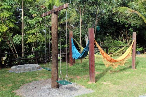 a couple of hammocks in a park with a cross at Pousada Nova Gironda in Paty do Alferes
