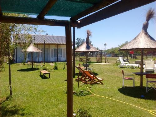 a yard with tables and chairs and umbrellas at Aitue Bungalows in Gualeguaychú