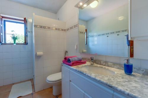 ein Badezimmer mit einem Waschbecken, einem WC und einem Spiegel in der Unterkunft Family House Lana in Osor