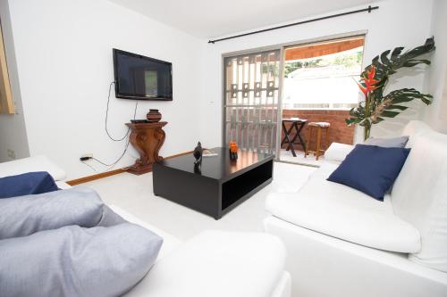 Sala de estar con 2 sofás blancos y TV en San Fernando Suite 201 - Livin Colombia, en Cali