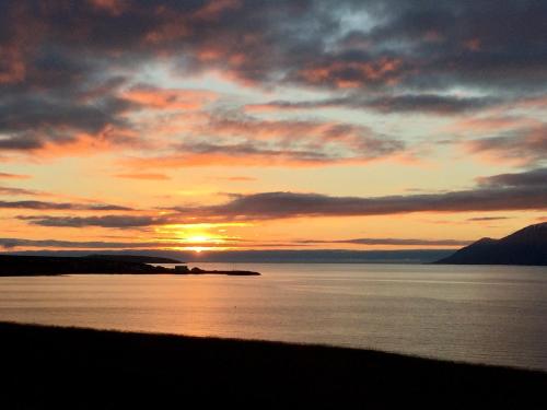 a sunset over a body of water with the sun setting at Ytri Vík in Hauganes