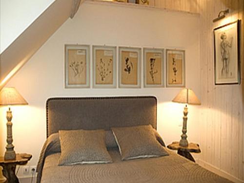 a bedroom with a bed with two lamps and pictures on the wall at Au Grey d'Honfleur in Honfleur