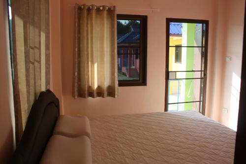 a bedroom with a bed and two windows at Panna Kalong in Chiang Khong