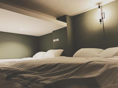 two white beds in a room with green walls at Urban in Kaohsiung