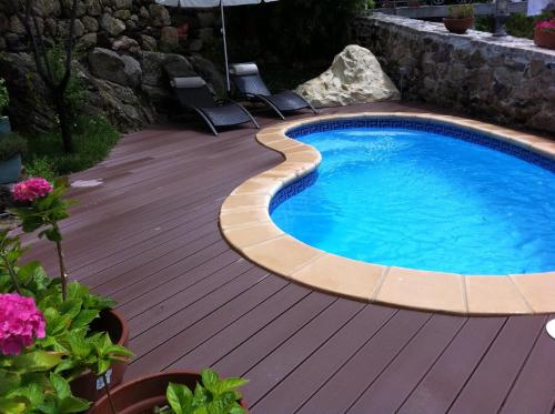 a swimming pool on a wooden deck with chairs around it at O Remanso Dos Patos in Penalba