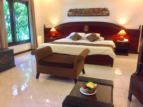 a bedroom with a bed and a chair and a table at Tamukami Hotel in Sanur