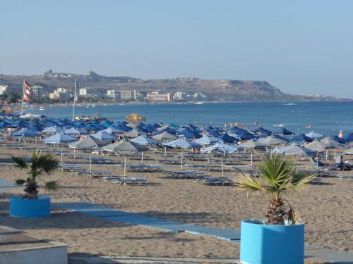 a beach with umbrellas and chairs and the ocean at Rea Hotel in Faliraki