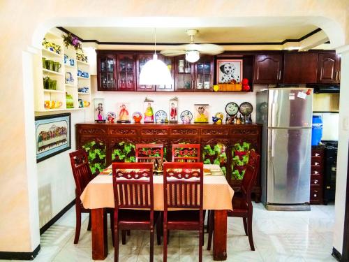 a kitchen with a table with chairs and a refrigerator at Entire House with 4 rooms near SM Molino and Vermosa Ayala in Imus