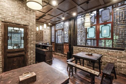 a room with tables and chairs and a brick wall at Elsewhere Hotel The former residence of the draft bank in Pingyao