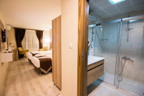 a bedroom with a bed and a bathroom with a shower at Hotel Business Han in Nevşehir