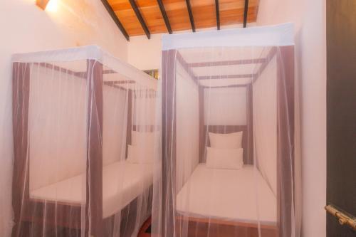 Kleines Zimmer mit 2 Etagenbetten und Vorhängen in der Unterkunft Red Parrot Beach Villa in Ambalangoda