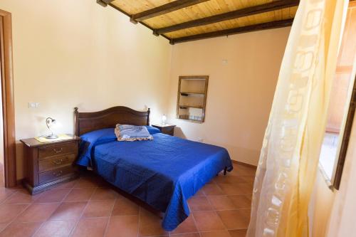 a bedroom with a bed with a blue bedspread at Profetina Village in Motta Camastra
