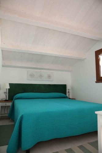 サンタンティーオコにあるAppartamento Lavandaのベッド1台(緑色のベッドカバー付)