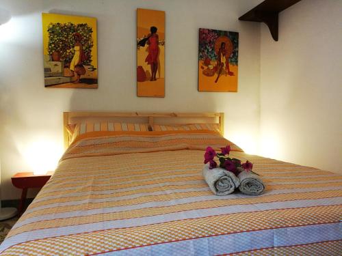 a bed with two towels and paintings on the wall at Casa e Giardino in San Giovanni la Punta