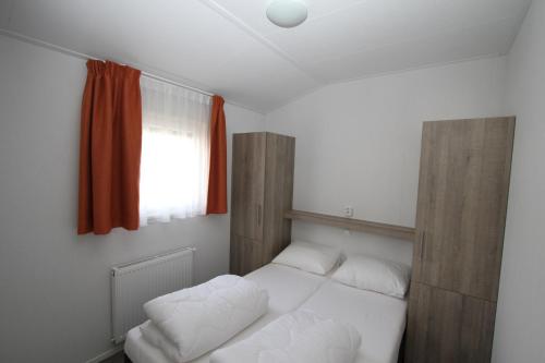 a bedroom with two white beds and a window at IJsselmeer-chalet nr. 66 in Molkwerum