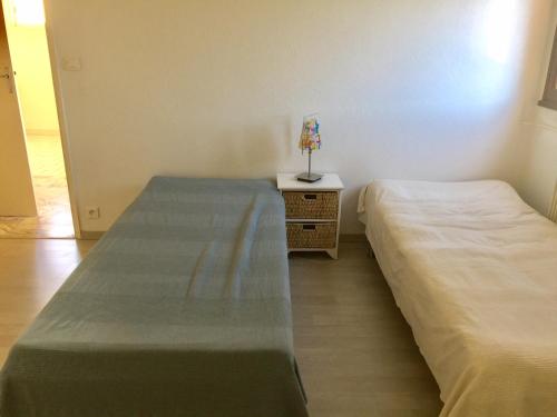 1 dormitorio con 2 camas y mesita de noche con lámpara en AGENCIA appartement 2 chambres LE CORFOU, en Cannes
