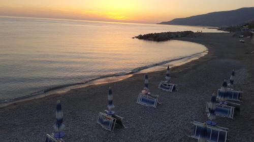 a group of lawn chairs on the beach at sunset at Sea Garden Hotel in Acquappesa