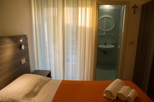 a bedroom with a bed and a bathroom with a sink at Hotel Madison in Gabicce Mare