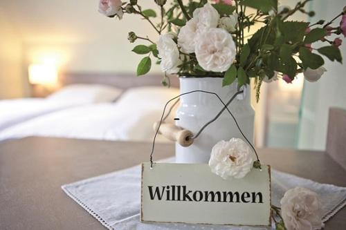 a white vase with flowers and a sign on a table at Hotel Landhaus Leuchtfeuer Nordseeinsel Pellworm in Pellworm
