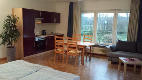 a living room with a kitchen and a table and chairs at Hotel Landhaus Leuchtfeuer Nordseeinsel Pellworm in Pellworm