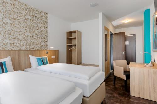 a hotel room with two beds and a desk at ibis Styles Arnsberg - Neheim in Arnsberg