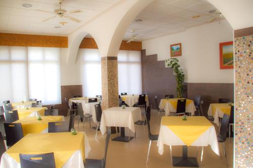 un comedor con mesas y sillas amarillas en Pensión Trinidad, en Guardamar del Segura