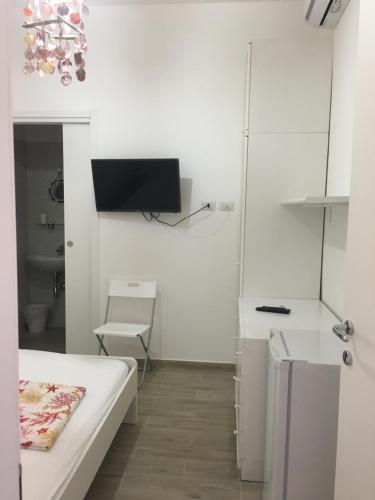 a white room with a bed and a tv on the wall at Villetta Sole in Bari Palese