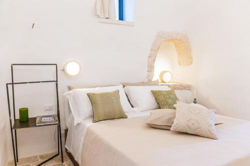 a white bedroom with a bed with white pillows at Borgo Canonica in Cisternino