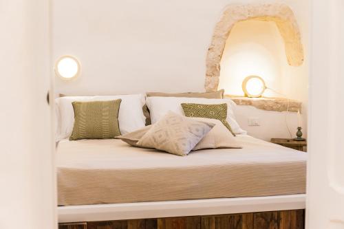 a bed with white sheets and pillows in a room at Borgo Canonica in Cisternino