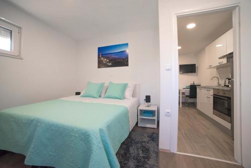 a white bedroom with a bed and a kitchen at Luxury apartments Petrovac in Sinj
