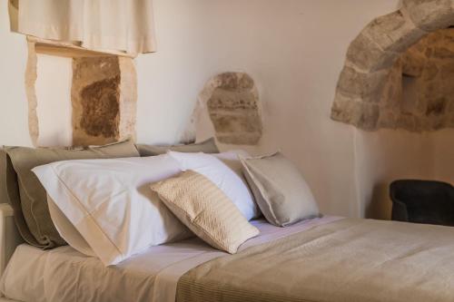 a bed with white sheets and pillows on it at Borgo Canonica in Cisternino