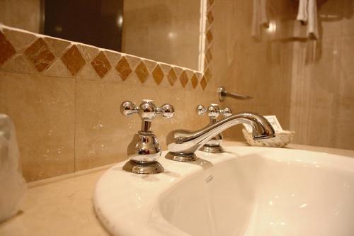 lavabo con grifo de plata y espejo en Hostería Posada del Sol, en Libertador General San Martín