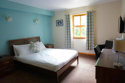 a bedroom with a bed and a chair and a window at Rob Roy Hotel in Aberfoyle