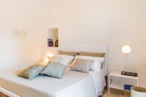 a bedroom with a white bed with pillows on it at Borgo Canonica in Cisternino