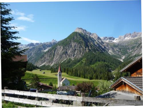 a village with a church and mountains in the background at Gasthaus Alpenrose in Gramais