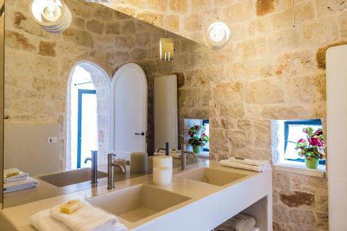 a bathroom with two sinks and a stone wall at Borgo Canonica in Cisternino