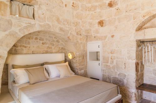 a bedroom with a bed in a stone wall at Borgo Canonica in Cisternino