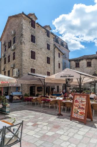 a patio with tables and umbrellas in front of a building at Hotel Rendez Vous in Kotor
