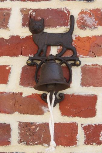 a bell on a brick wall with a black cat on it at De Rankhove in Herne