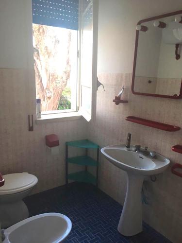 a bathroom with a sink and a toilet and a window at Blu Mare Villa Carlo in Anzio